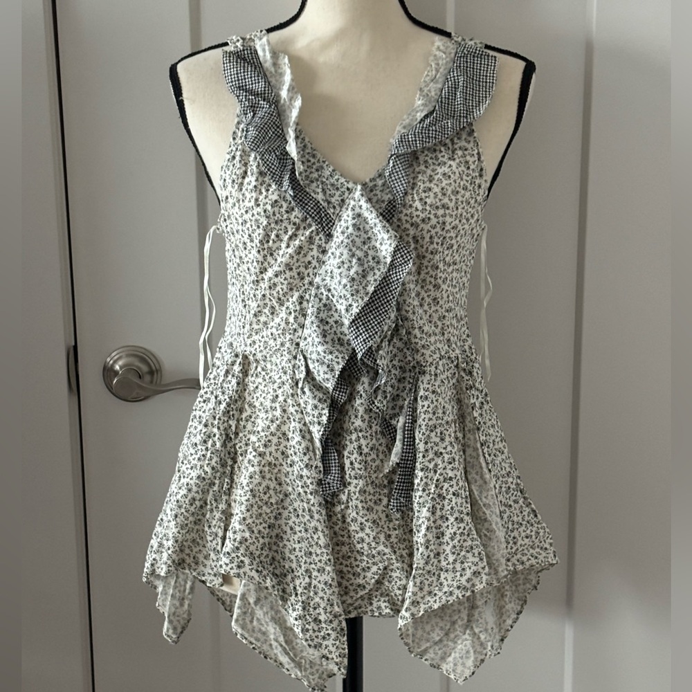Sleeveless tank top with ruffle detail down the front. Hip length and flowing